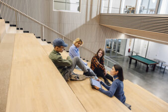 Aikuinen keskustelee kolmen nuoren kanssa koulun tiloissa.